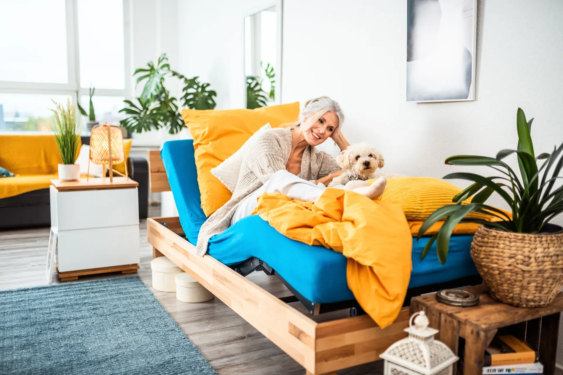 Frau liegt entspannt mit Hund auf einem verstellbaren Bett – ergonomische Schlafposition zur Entlastung des Rückens.