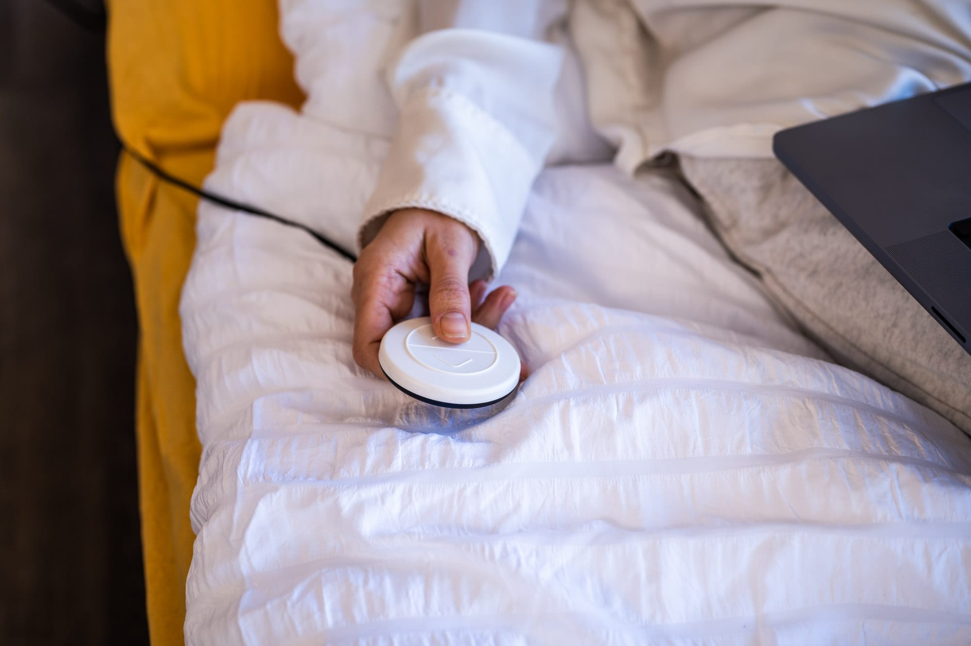 Hand hält die Fernbedienung von dem CosyLift, um die Matratze im Bett elektrisch zu verstellen