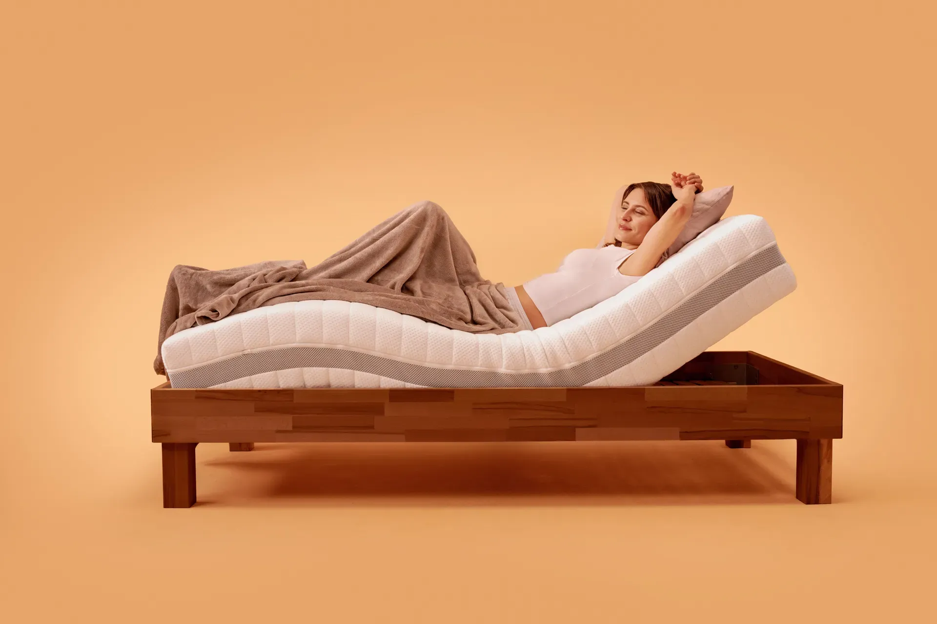 Frau liegt auf einer verstellbaren Matratze, die die Liegefläche ohne separaten Lattenrost anhebt