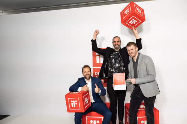 Drei Männer feiern mit Urkunde und roten iF-Design-Award-Würfeln den Gewinn des iF Design Award 2023 für den CosyLift.