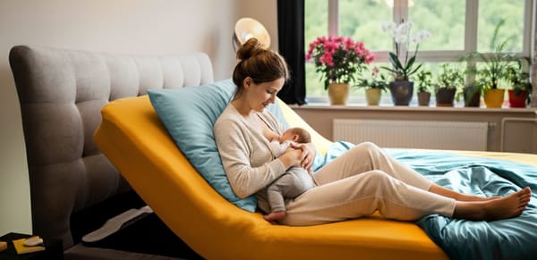 Mutter stillt ihr Baby in einer ergonomisch angehobenen Halbsitzposition mit dem CosyLift unter der Matratze.